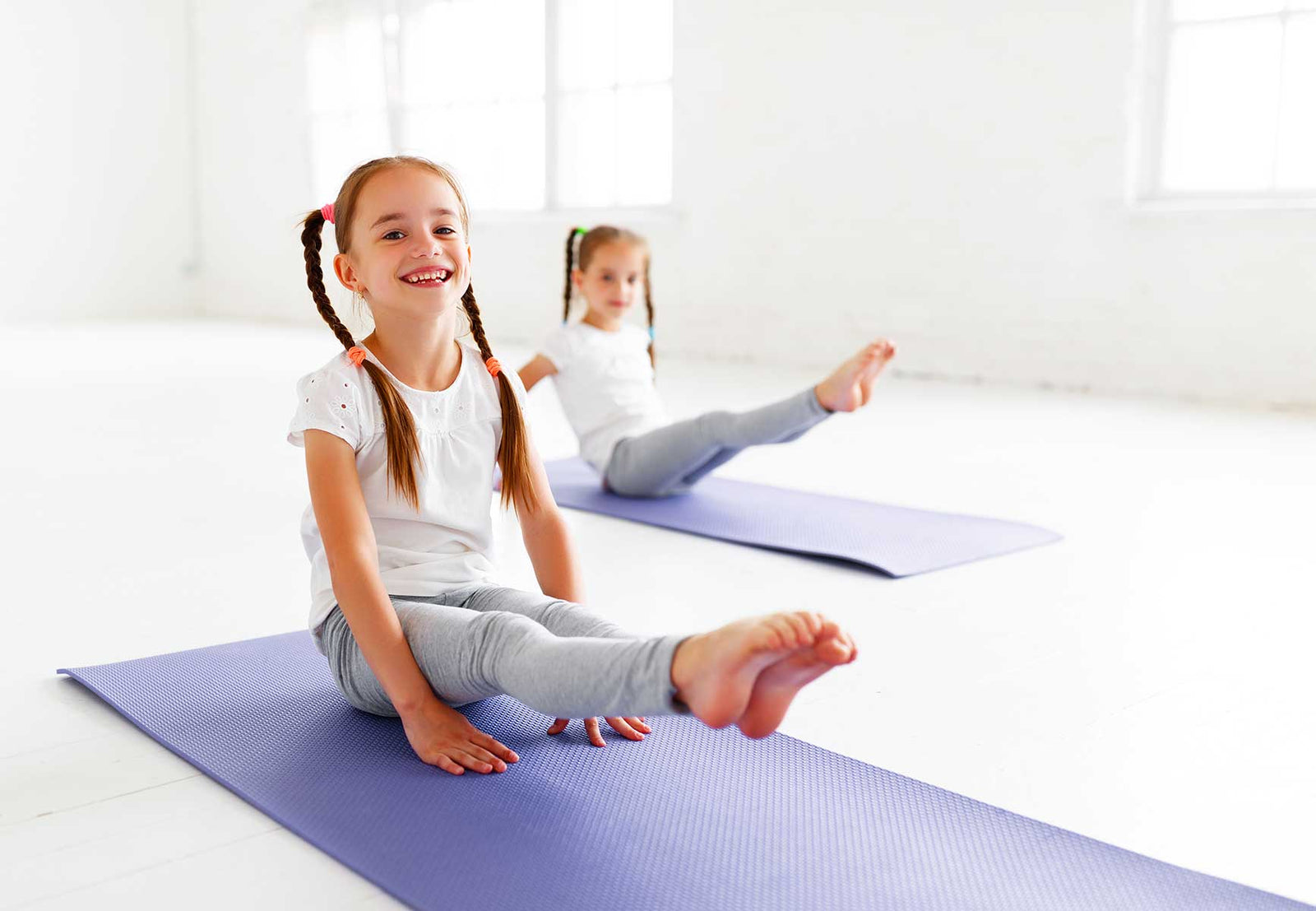 Kind übt Yoga auf einer bunten Kinderyogamatte